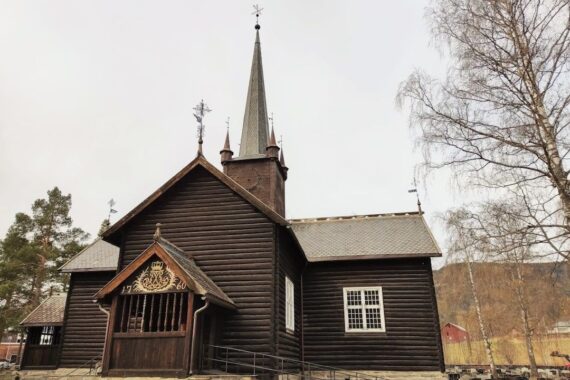 Mörk träkyrka med spånklädda tak och hög spetsig tornspira